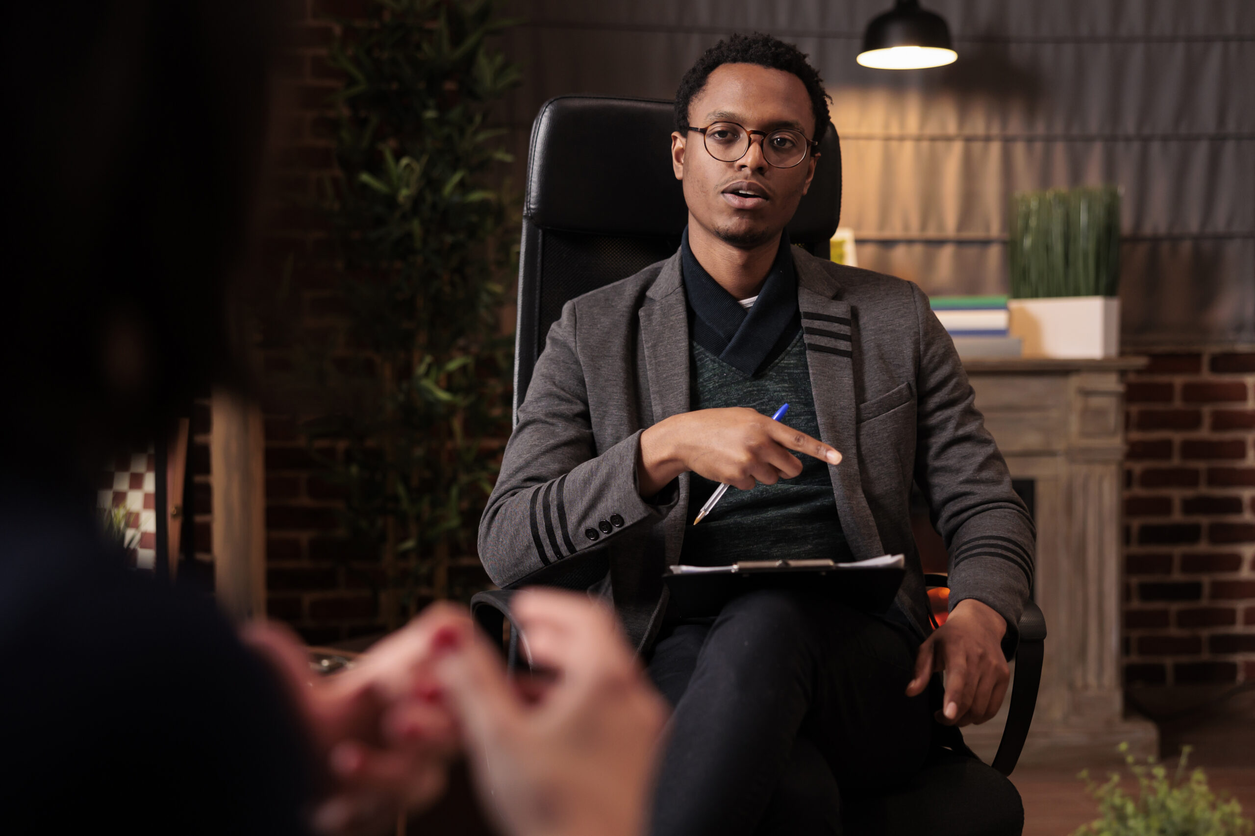 Male psychotherapist doing psychoanalysis consultation with couple at therapy session in office. Giving relationship advice to solve conflict between angry partners, counseling support.